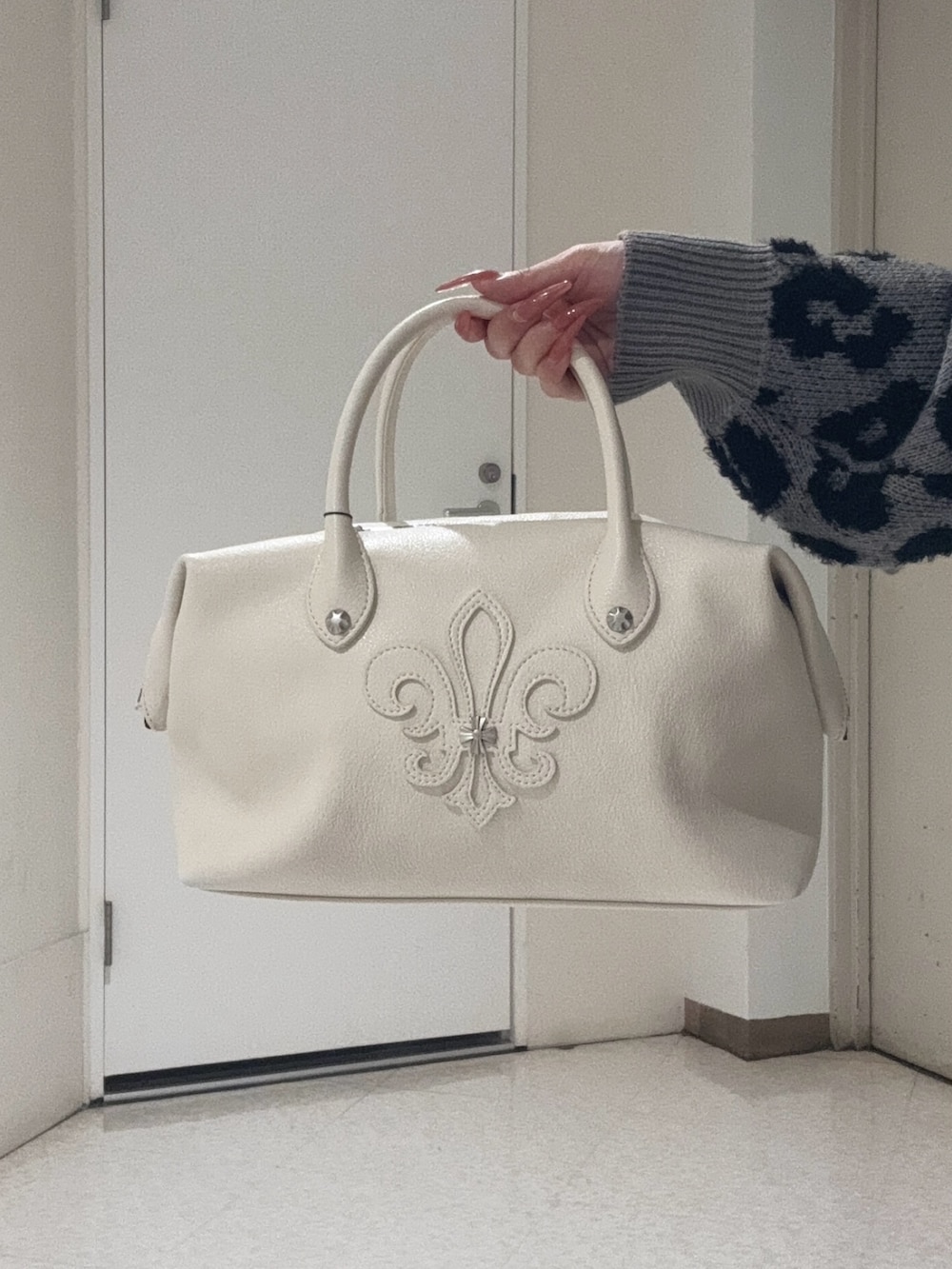 グレー系のカーディガン/ボレロ、ホワイト系のボストンバッグ、ブラック系のブーツを着用したレディースの冬コーディネートの4枚目の写真