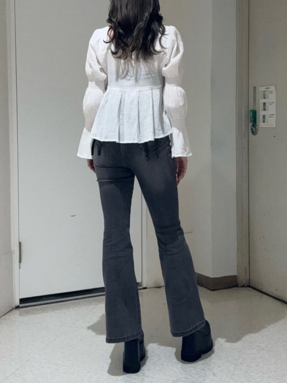 ブラック系のブーツ、ブラック系のデニムパンツ、ブラック系のショルダーバッグを着用したレディースの春コーディネートの3枚目の写真