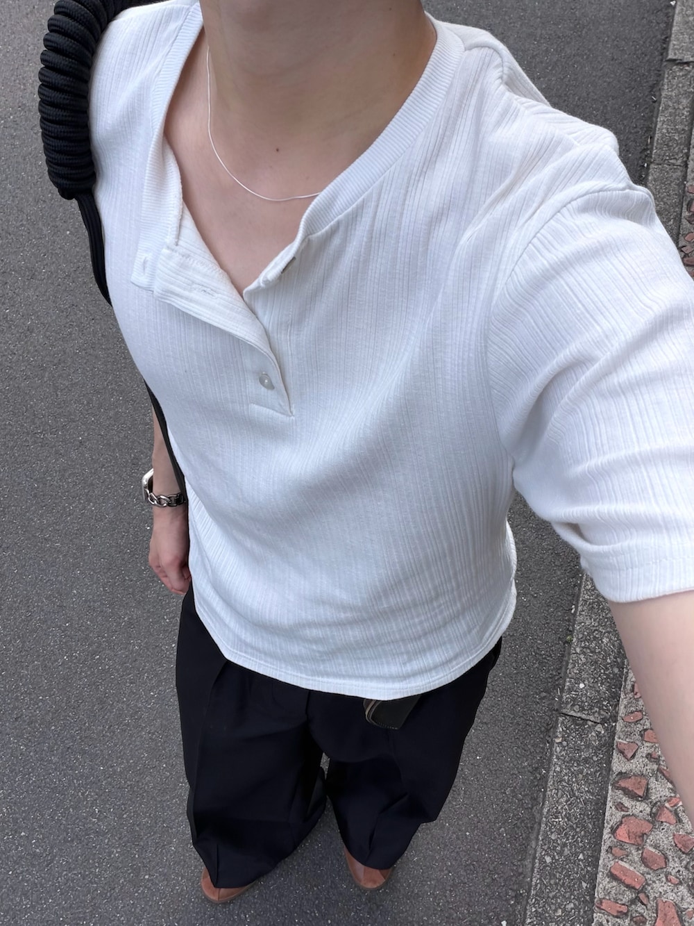 ブラウン系のスニーカー、ホワイト系のTシャツ/カットソー、ブラック系のスラックスを着用したメンズの夏コーディネートの2枚目の写真