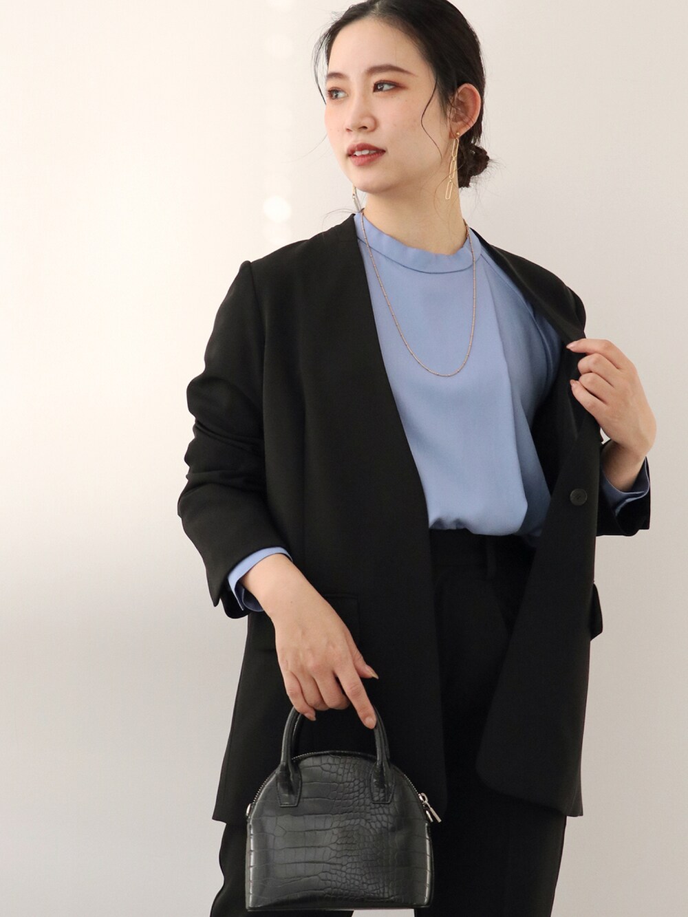 ブラック系のスラックス、ブラック系のノーカラージャケット、ブルー系のシャツ/ブラウスを着用したレディースの冬コーディネートの4枚目の写真