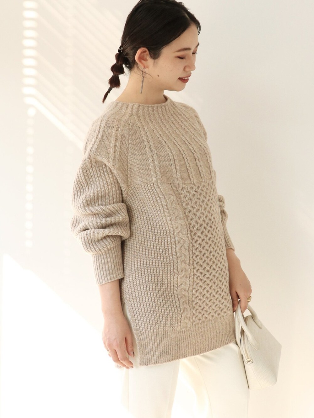 ベージュ系のニット/セーター、ホワイト系のスラックス、ホワイト系のショルダーバッグを着用したレディースの冬コーディネートの3枚目の写真