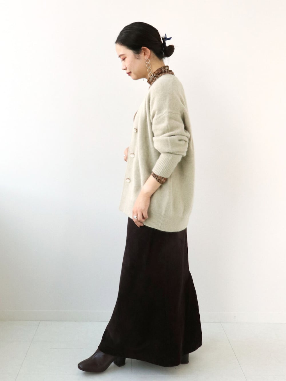 ブラウン系のTシャツ/カットソー、ベージュ系のニット/セーター、ブラウン系のスカートを着用したレディースの冬コーディネートの2枚目の写真