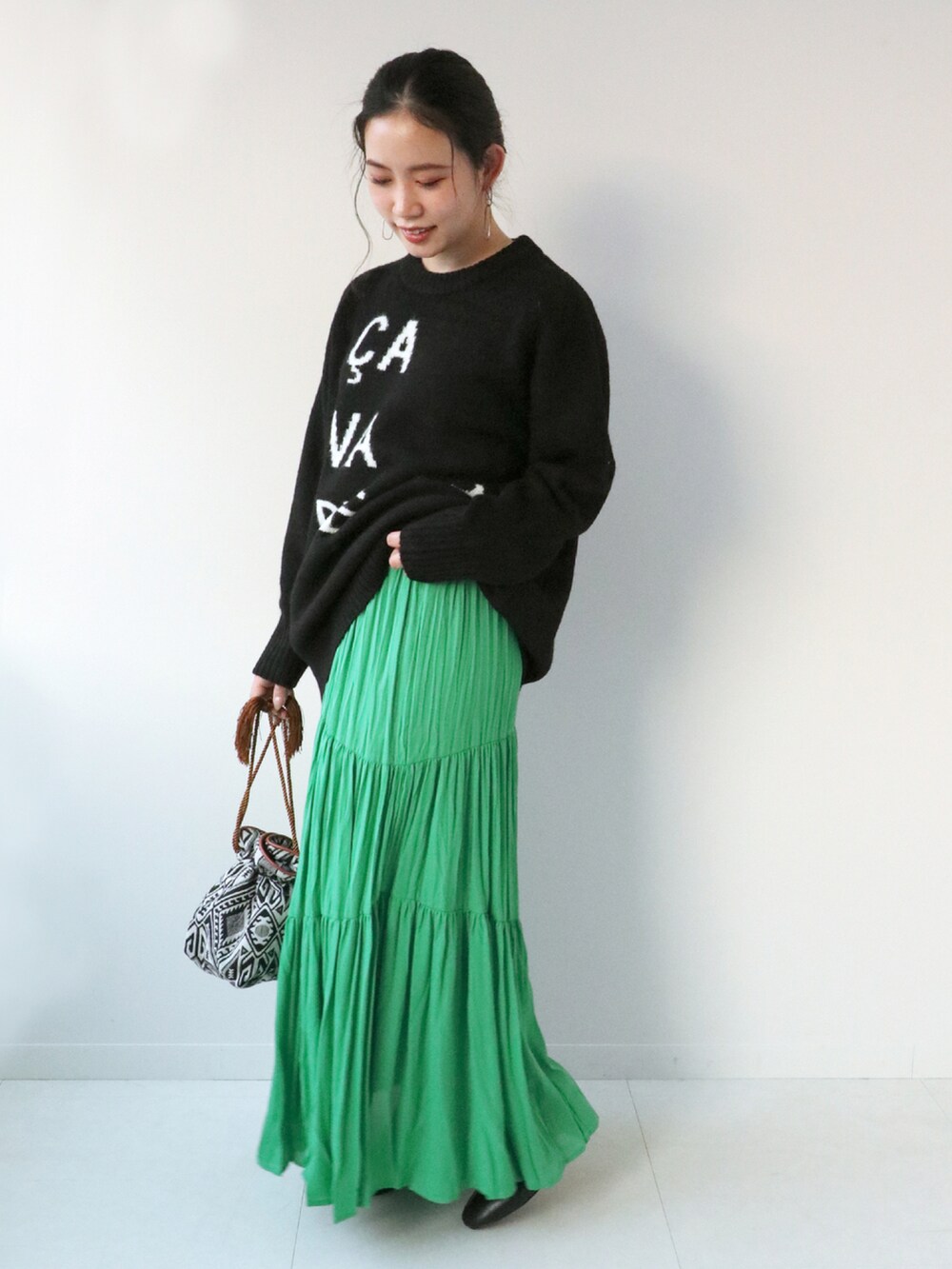 ブラック系のニット/セーター、グリーン系のスカート、ブラック系のショルダーバッグを着用したレディースの冬コーディネートの2枚目の写真