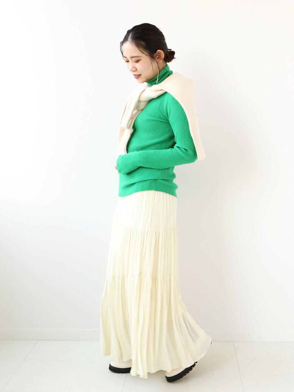 グリーン系のニット/セーター、ホワイト系のニット/セーター、ベージュ系のスカートを着用したレディースの冬コーディネートの2枚目の写真
