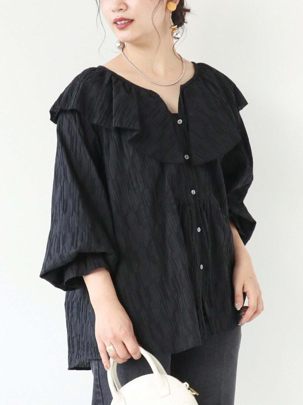 ブラック系のシャツ/ブラウス、ブラック系のデニムパンツ、ホワイト系のショルダーバッグを着用したレディースの秋コーディネートの4枚目の写真