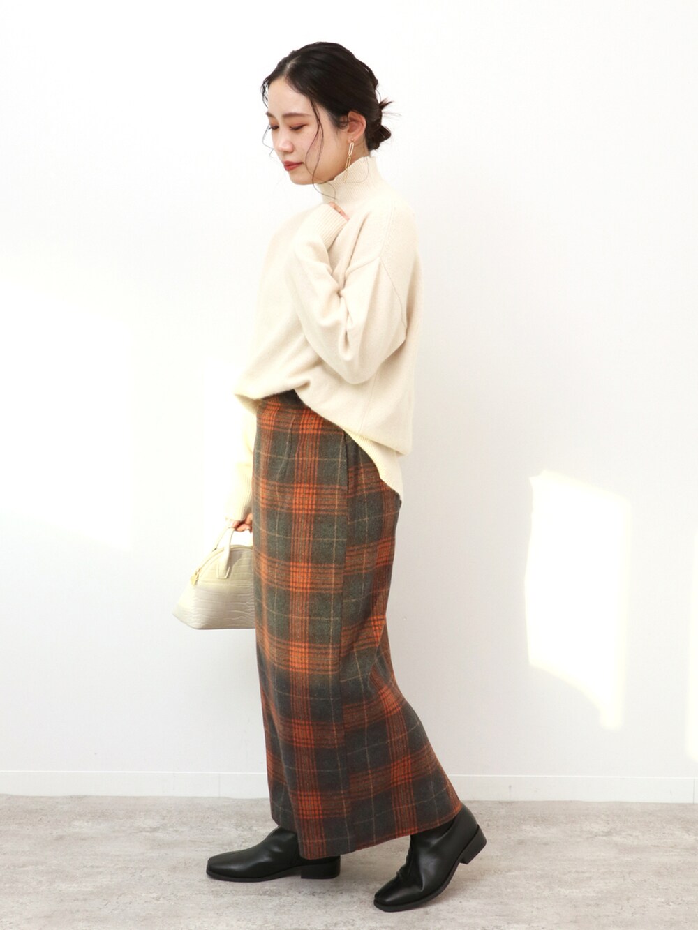 ホワイト系のショルダーバッグ、ブラウン系のスカート、ホワイト系のニット/セーターを着用したレディースの冬コーディネートの2枚目の写真