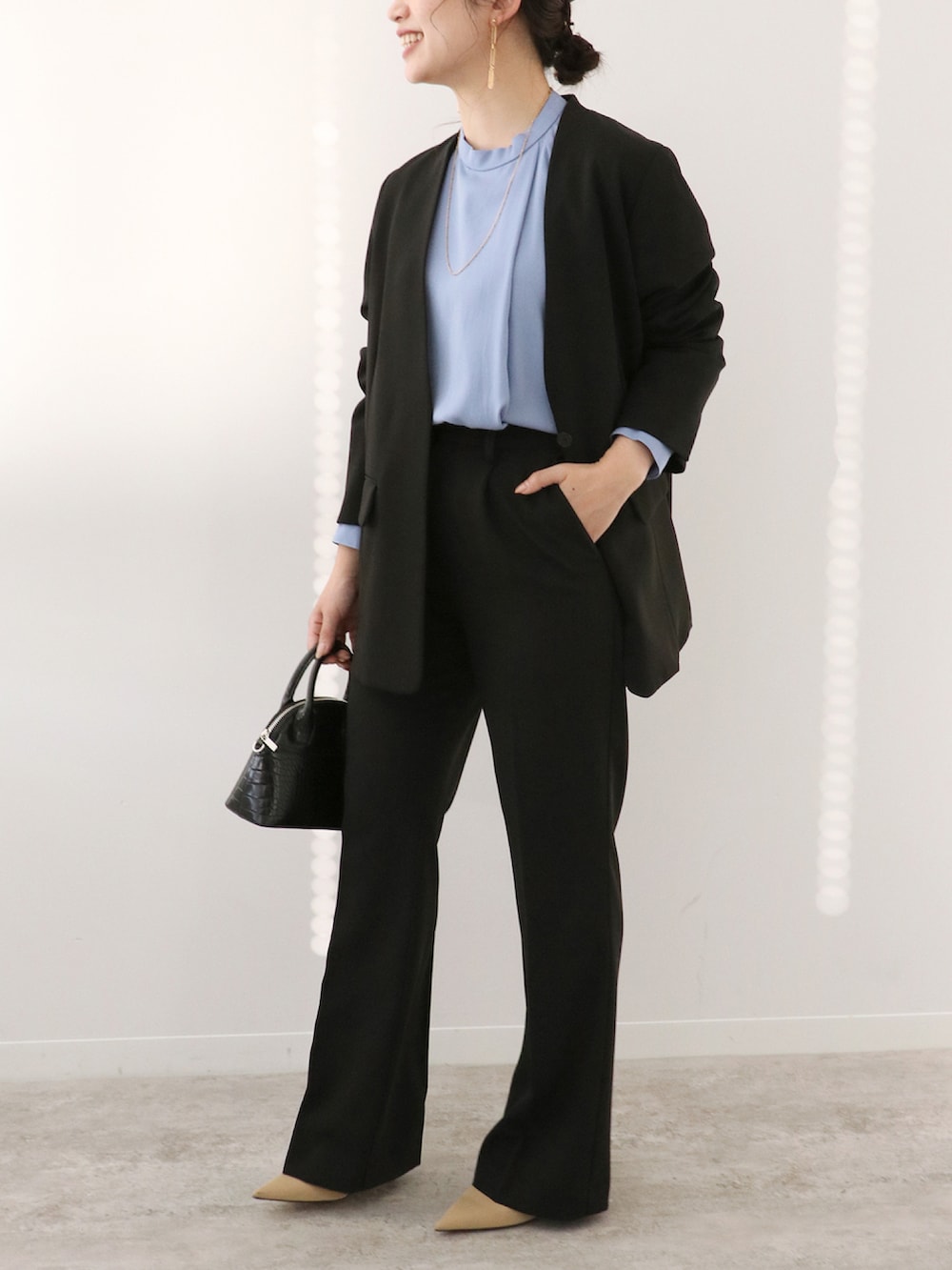 ブラック系のスラックス、ブラック系のノーカラージャケット、ブルー系のシャツ/ブラウスを着用したレディースの冬コーディネートの3枚目の写真