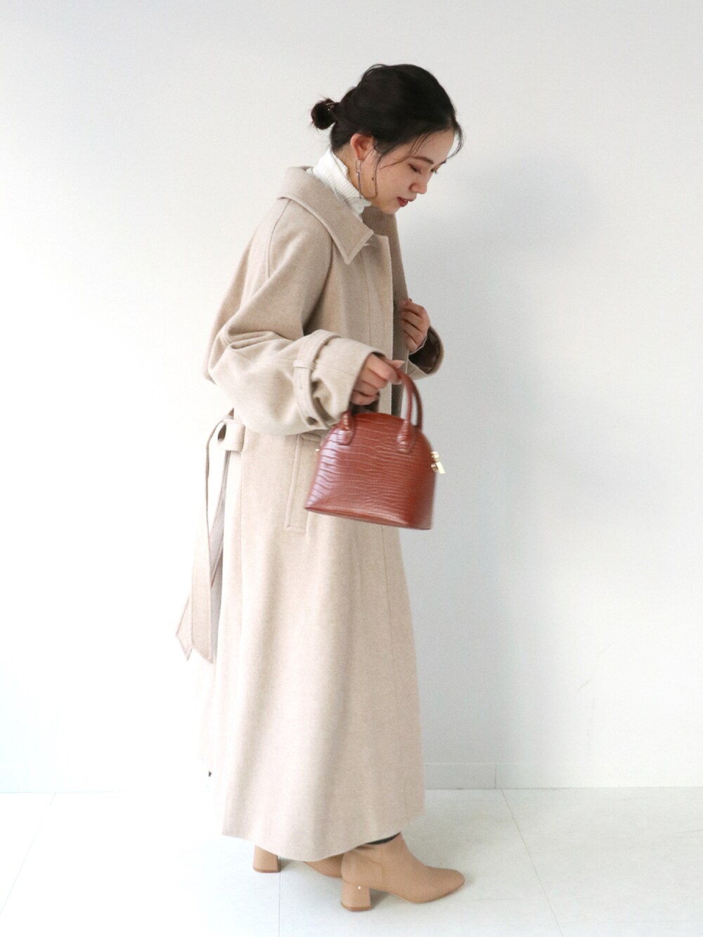 ブラウン系のスカート、ベージュ系のステンカラーコート、ホワイト系のニット/セーターを着用したレディースの冬コーディネートの4枚目の写真