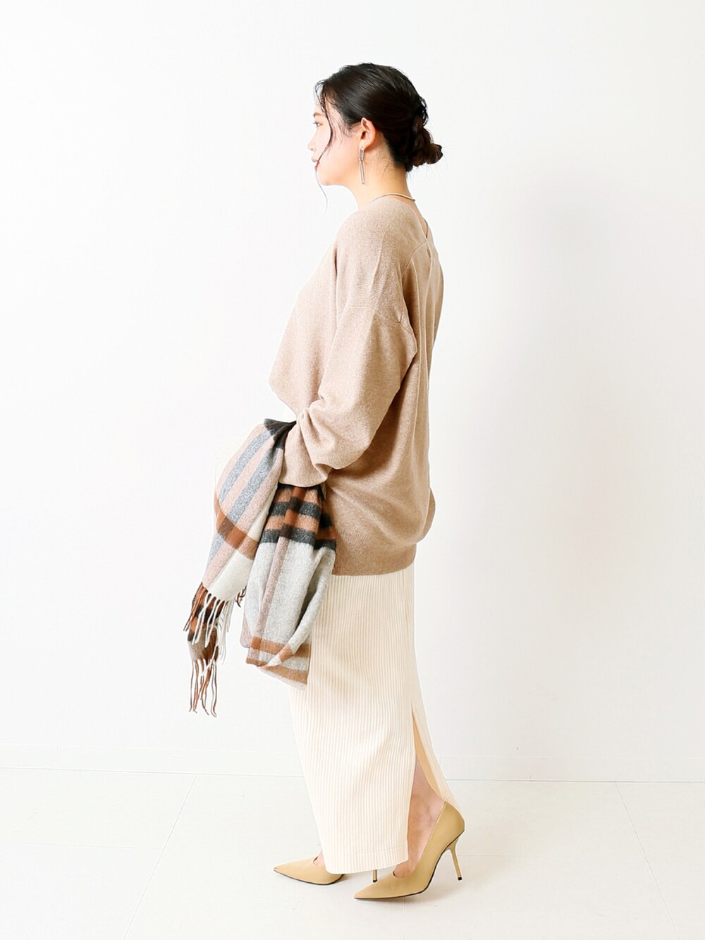 ベージュ系のニット/セーター、ホワイト系のスカート、ブラウン系のマフラーを着用したレディースの冬コーディネートの2枚目の写真