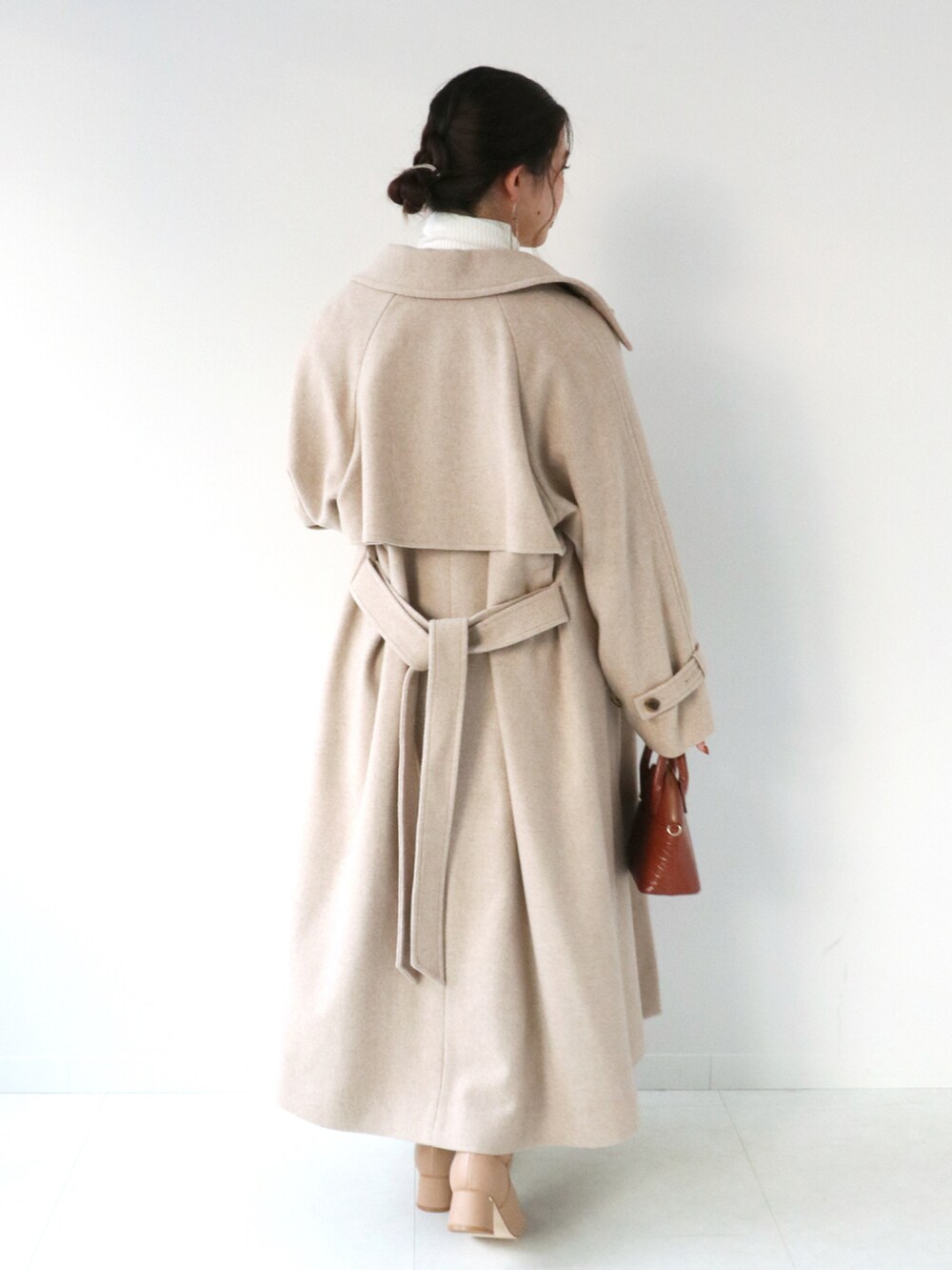 ブラウン系のスカート、ベージュ系のステンカラーコート、ホワイト系のニット/セーターを着用したレディースの冬コーディネートの3枚目の写真