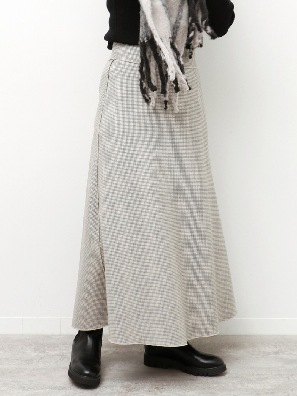 ブラック系のニット/セーター、ベージュ系のスカート、ブラック系のマフラーを着用したレディースの冬コーディネートの5枚目の写真