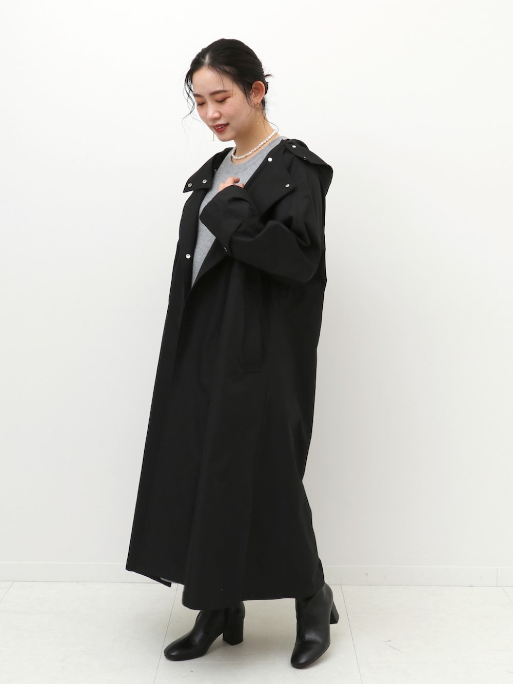 グレー系のワンピース、ブラック系のノーカラーコートを着用したレディースの冬コーディネートの2枚目の写真