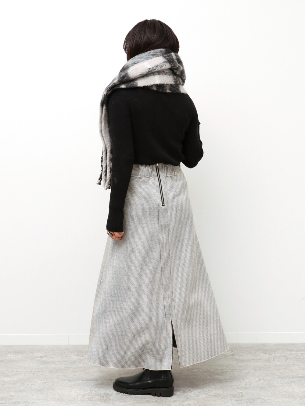 ブラック系のニット/セーター、ベージュ系のスカート、ブラック系のマフラーを着用したレディースの冬コーディネートの3枚目の写真