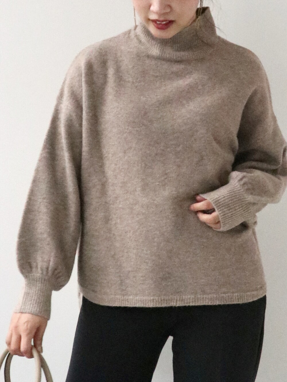 ブラウン系のニット/セーター、ブラック系のパンツ、ベージュ系のバッグを着用したレディースの秋コーディネートの2枚目の写真