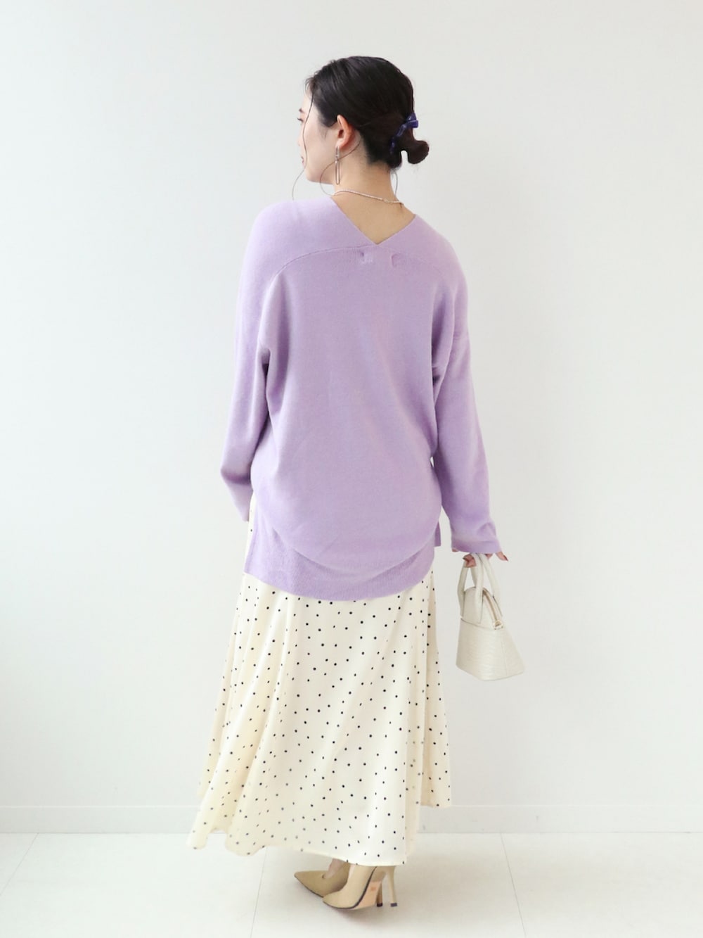 ホワイト系のショルダーバッグ、ホワイト系のスカート、パープル系のニット/セーターを着用したレディースの秋コーディネートの2枚目の写真
