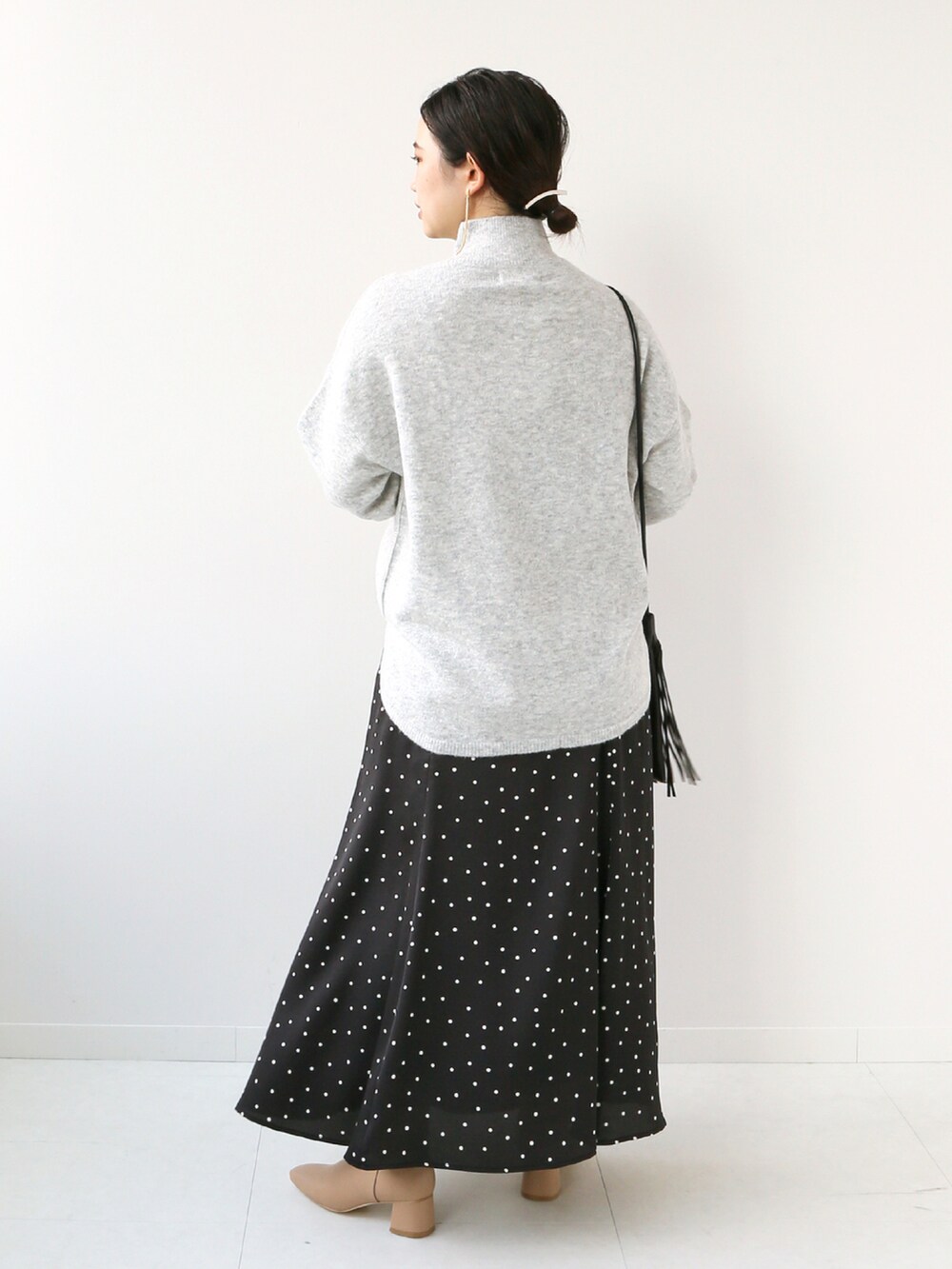 ブラック系のスカート、グレー系のニット/セーターを着用したレディースの秋コーディネートの2枚目の写真