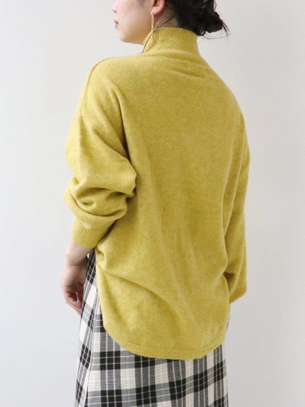 イエロー系のニット/セーター、ベージュ系のスカートを着用したレディースの秋コーディネートの3枚目の写真