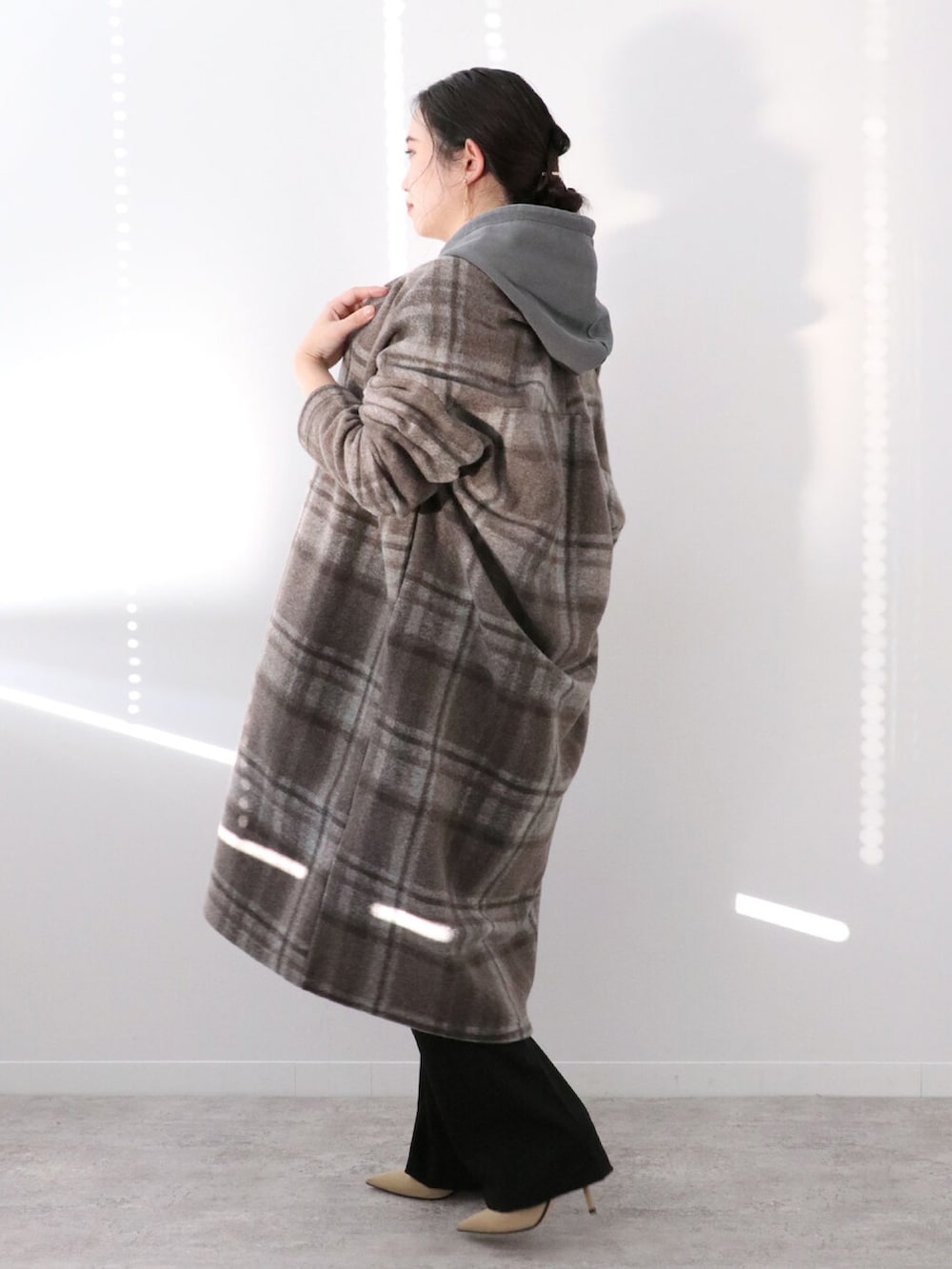 ブラック系のパーカー、ブラウン系のその他アウター、ブラック系のスラックスを着用したレディースの冬コーディネートの2枚目の写真