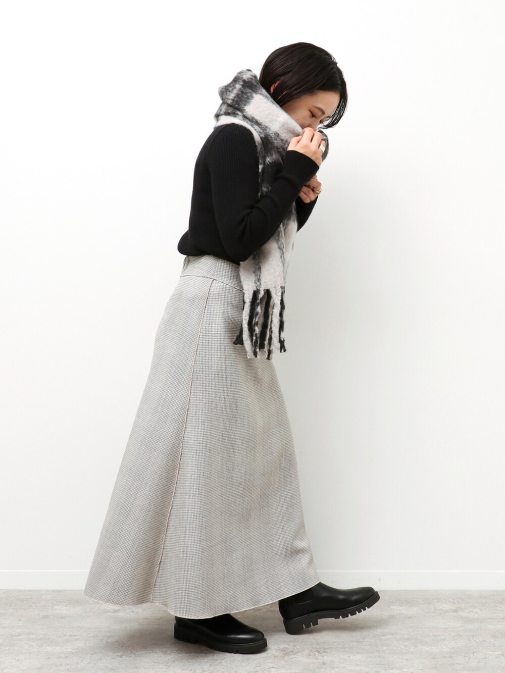 ブラック系のニット/セーター、ベージュ系のスカート、ブラック系のマフラーを着用したレディースの冬コーディネートの4枚目の写真