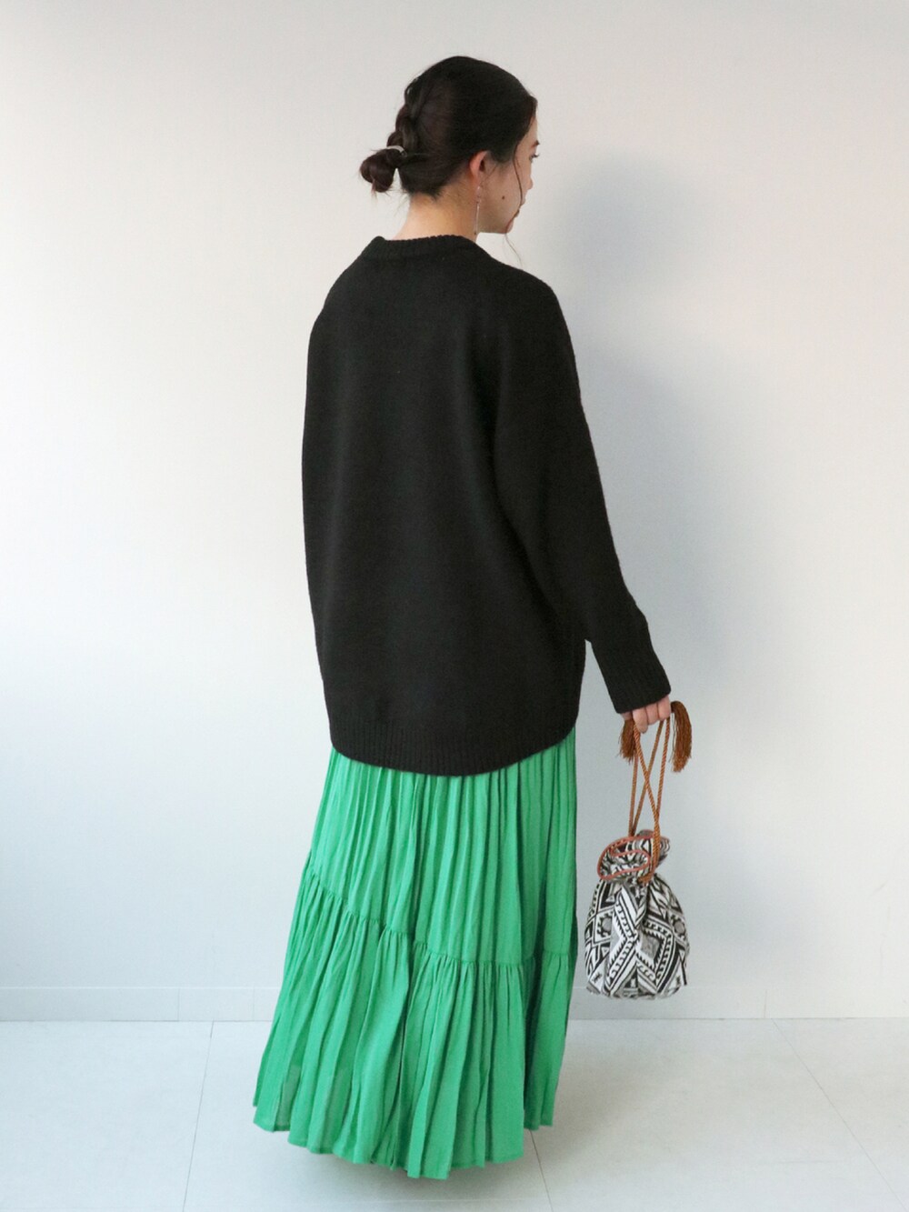 ブラック系のニット/セーター、グリーン系のスカート、ブラック系のショルダーバッグを着用したレディースの冬コーディネートの4枚目の写真