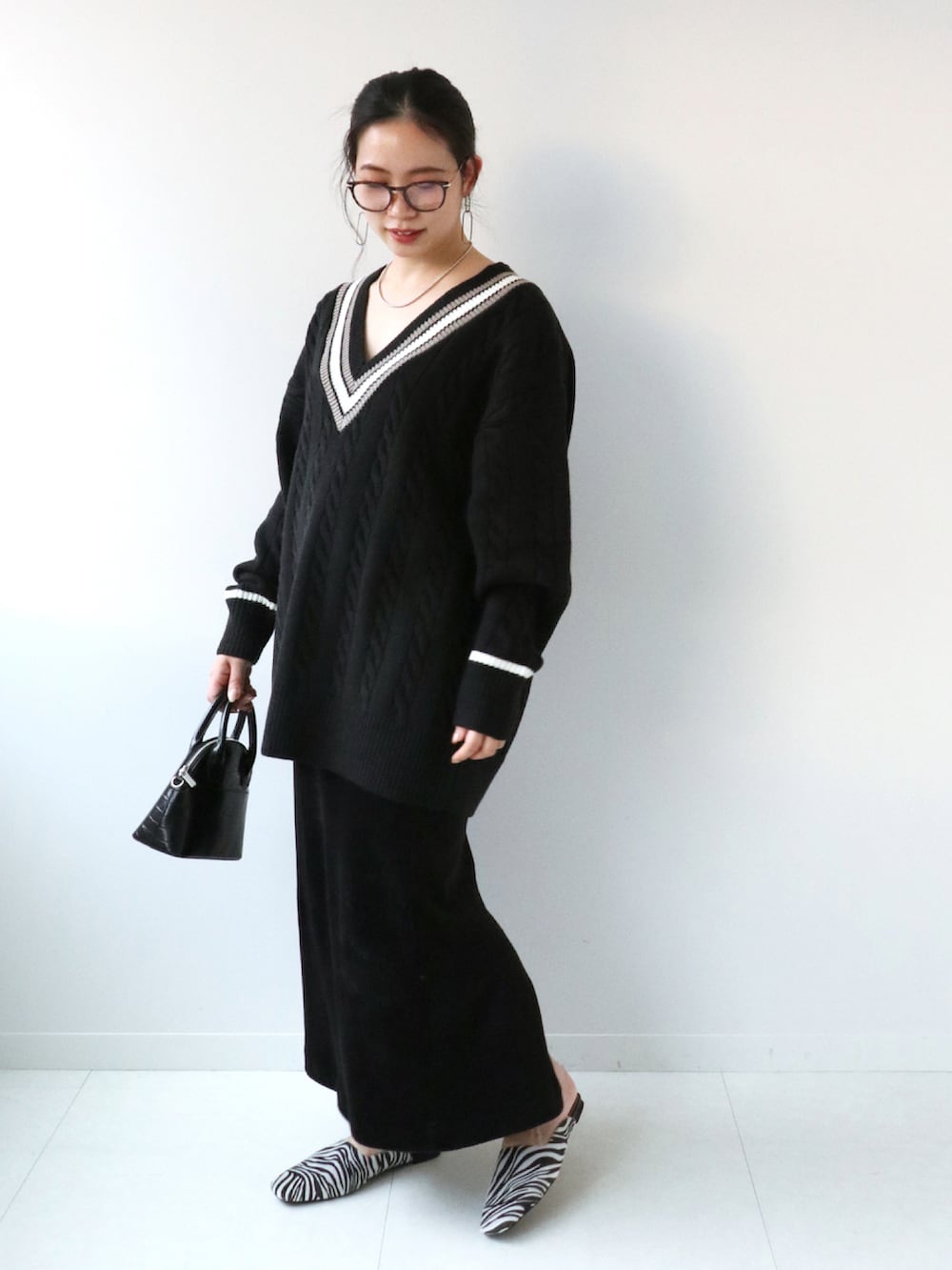 ブラック系のショルダーバッグ、ブラック系のスリッポン、ブラック系のスカートを着用したレディースの冬コーディネートの3枚目の写真