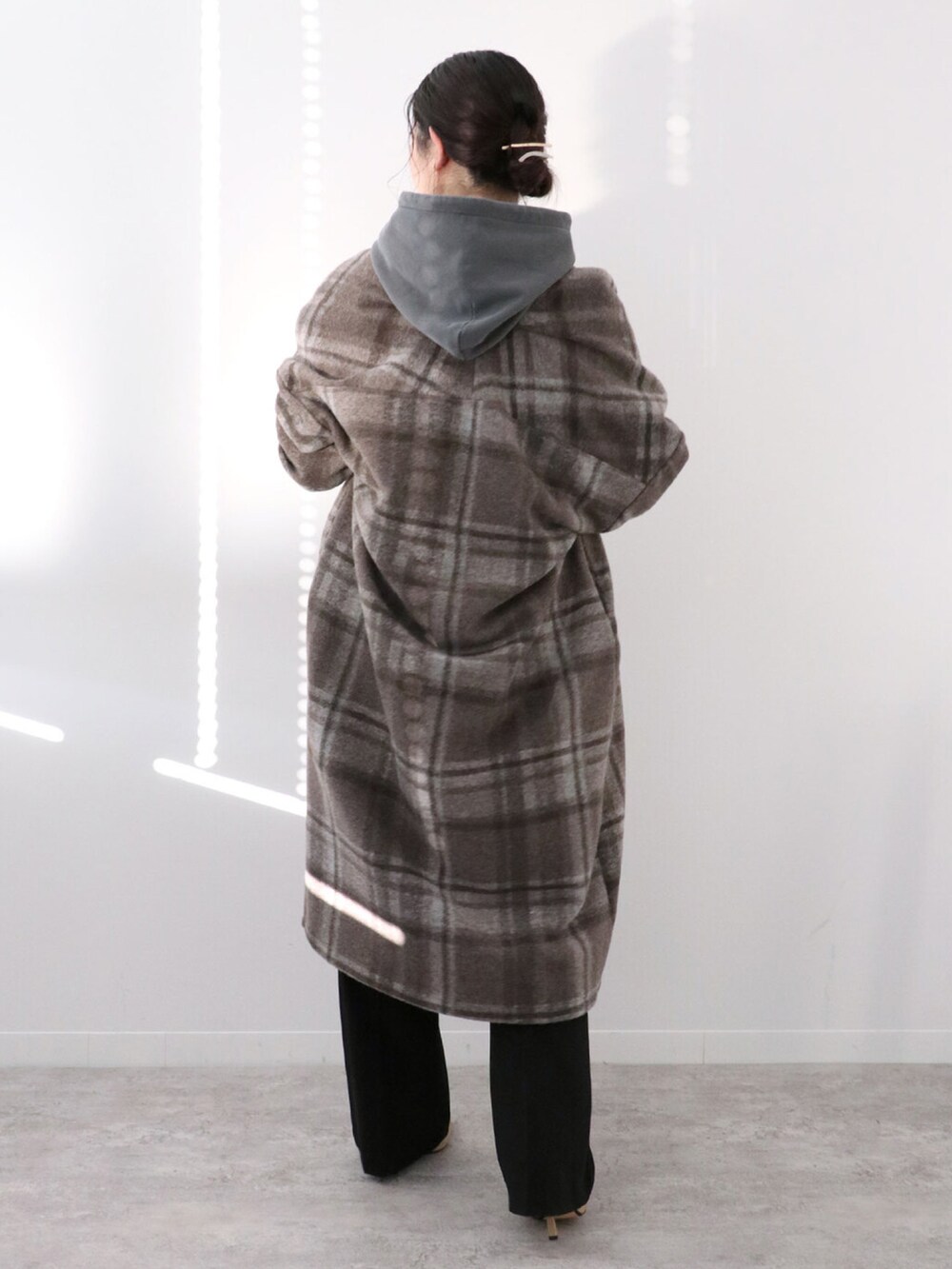 ブラック系のパーカー、ブラウン系のその他アウター、ブラック系のスラックスを着用したレディースの冬コーディネートの3枚目の写真