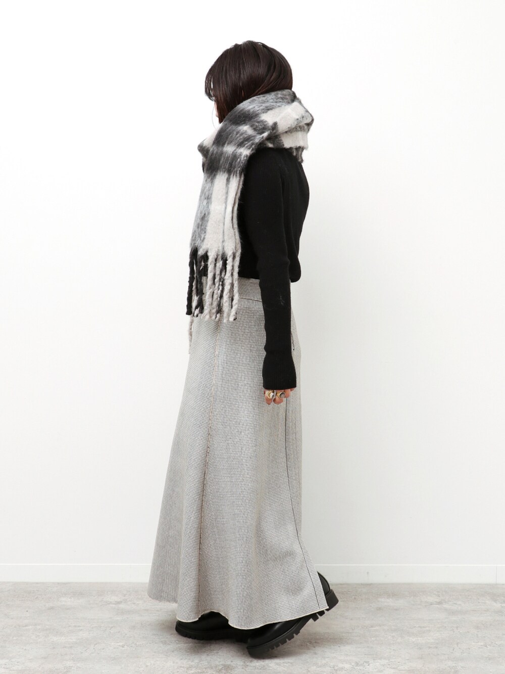 ブラック系のニット/セーター、ベージュ系のスカート、ブラック系のマフラーを着用したレディースの冬コーディネートの2枚目の写真