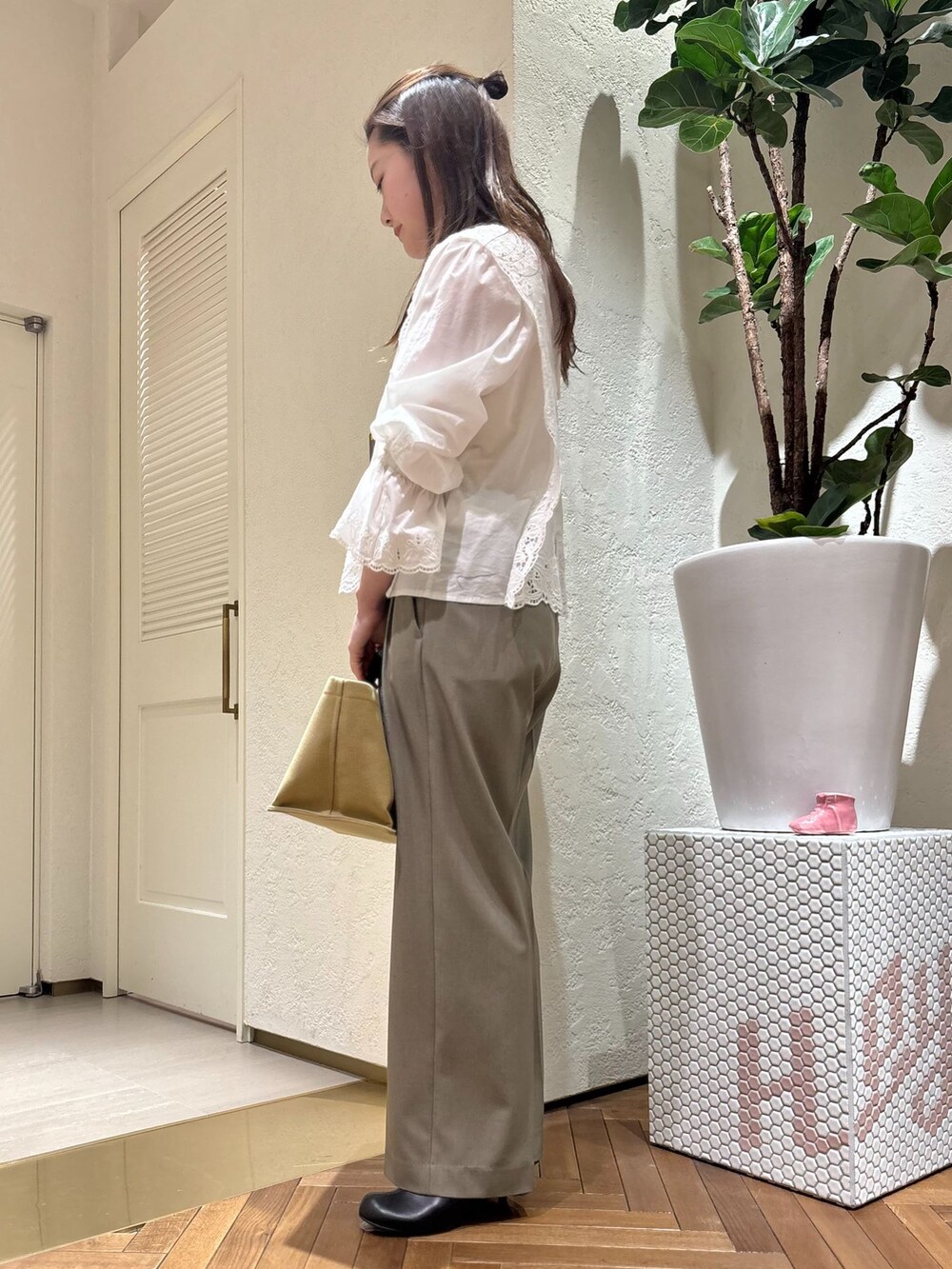 グリーン系のスラックス、ホワイト系のシャツ/ブラウス、ベージュ系のトートバッグを着用したレディースの春コーディネートの2枚目の写真
