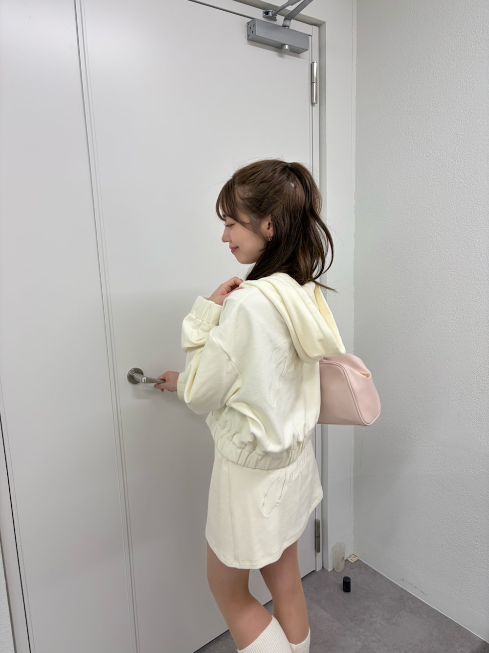 ホワイト系のパーカー、ホワイト系のスカート、ピンク系のボストンバッグを着用したレディースの冬コーディネートの3枚目の写真