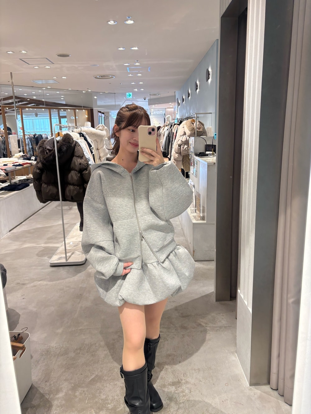 グレー系のパーカー、グレー系のスカート、ブラック系のブーツを着用したレディースの冬コーディネートの3枚目の写真