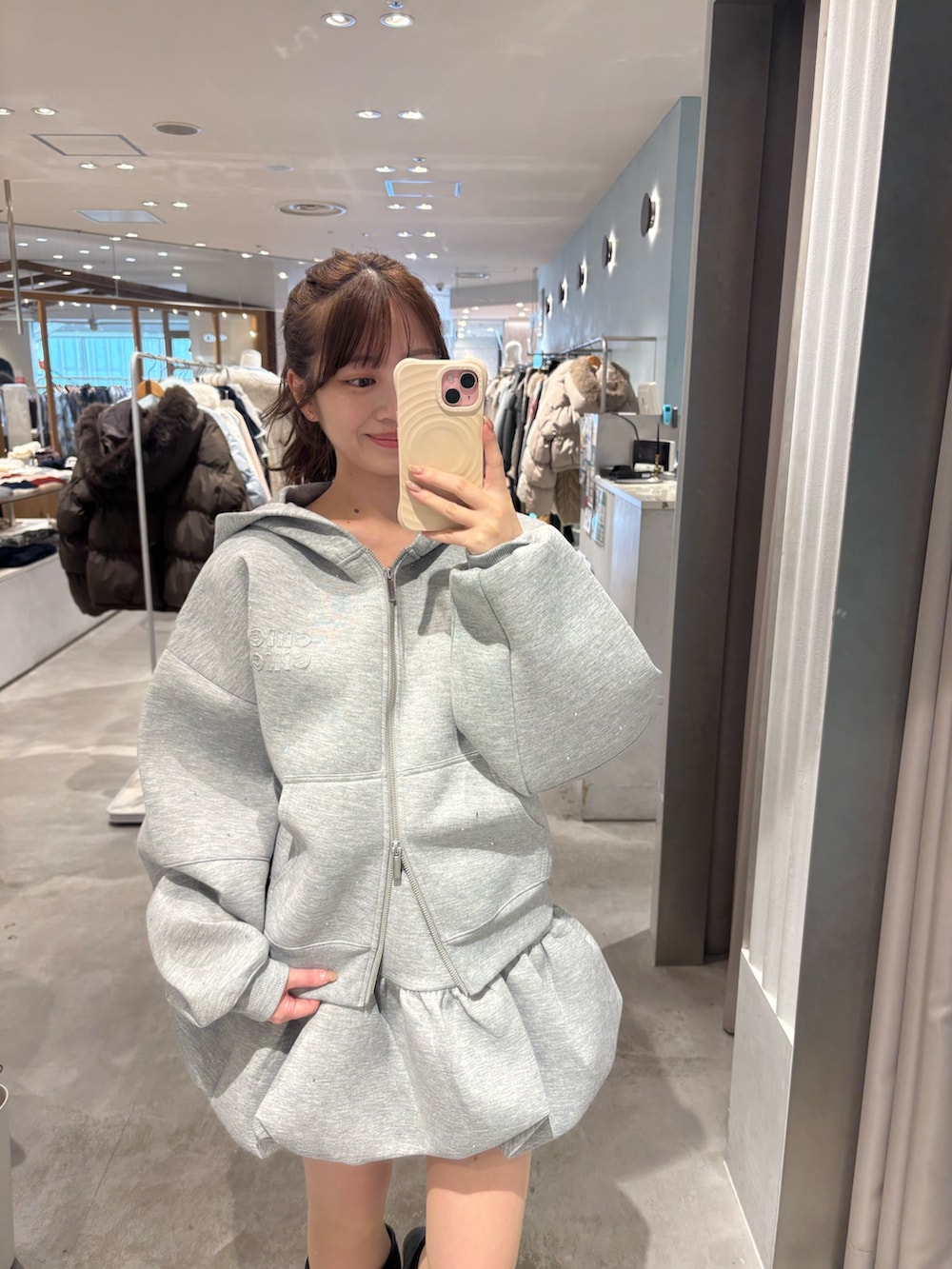 グレー系のパーカー、グレー系のスカート、ブラック系のブーツを着用したレディースの冬コーディネートの2枚目の写真