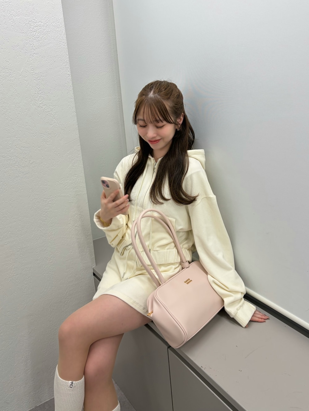 ホワイト系のパーカー、ホワイト系のスカート、ピンク系のボストンバッグを着用したレディースの冬コーディネートの2枚目の写真