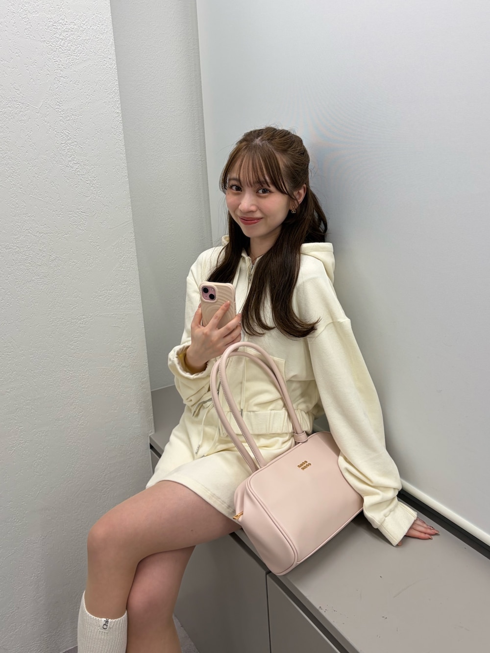 ホワイト系のパーカー、ホワイト系のスカート、ピンク系のボストンバッグを着用したレディースの冬コーディネートの5枚目の写真