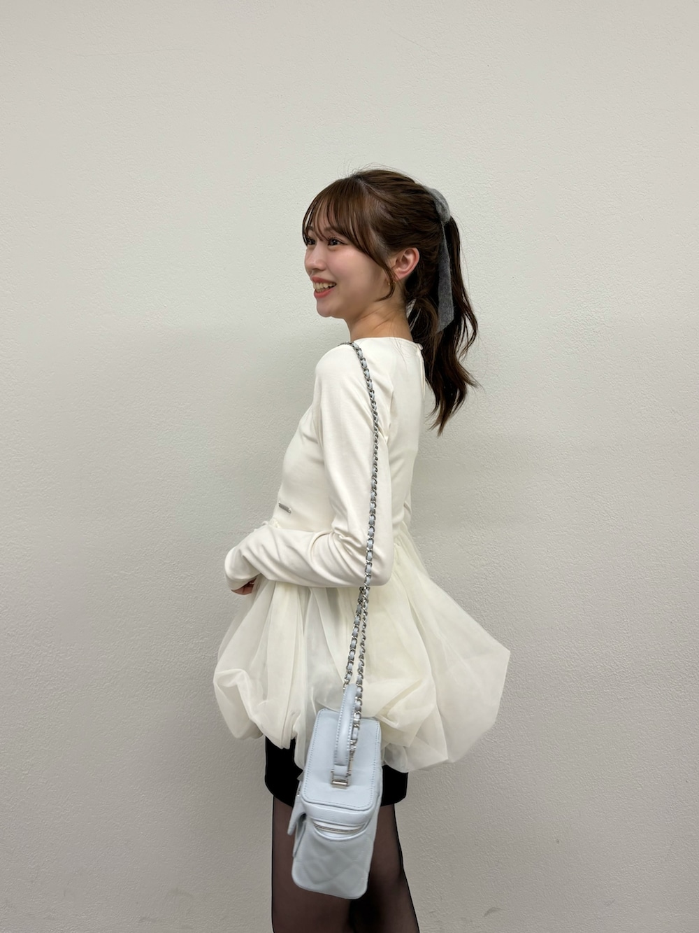 ホワイト系のTシャツ/カットソー、ブラック系のパンプス、ブルー系のショルダーバッグを着用したレディースの冬コーディネートの5枚目の写真