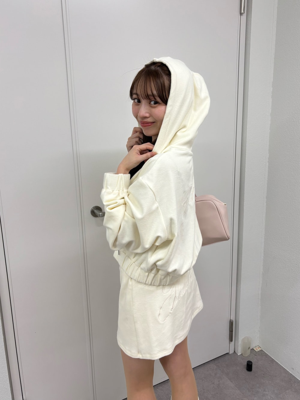 ホワイト系のパーカー、ホワイト系のスカート、ピンク系のボストンバッグを着用したレディースの冬コーディネートの4枚目の写真