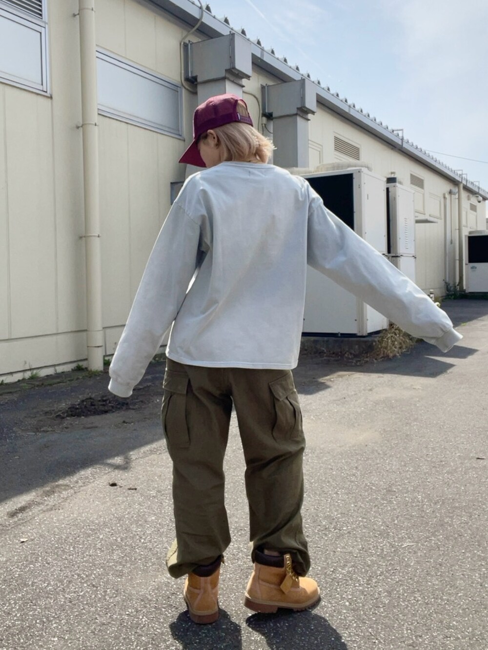 グレー系のTシャツ/カットソー、グリーン系のカーゴパンツ、レッド系のキャップを着用したレディースの春コーディネートの2枚目の写真