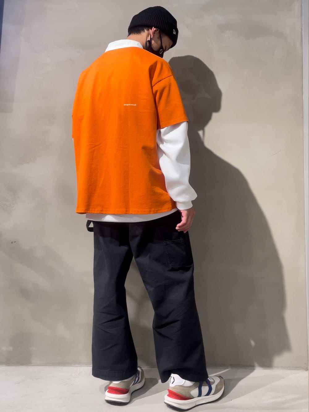 オレンジ系のTシャツ/カットソー、ホワイト系のトップス、ブラック系のチノパンツを着用したメンズの冬コーディネートの2枚目の写真