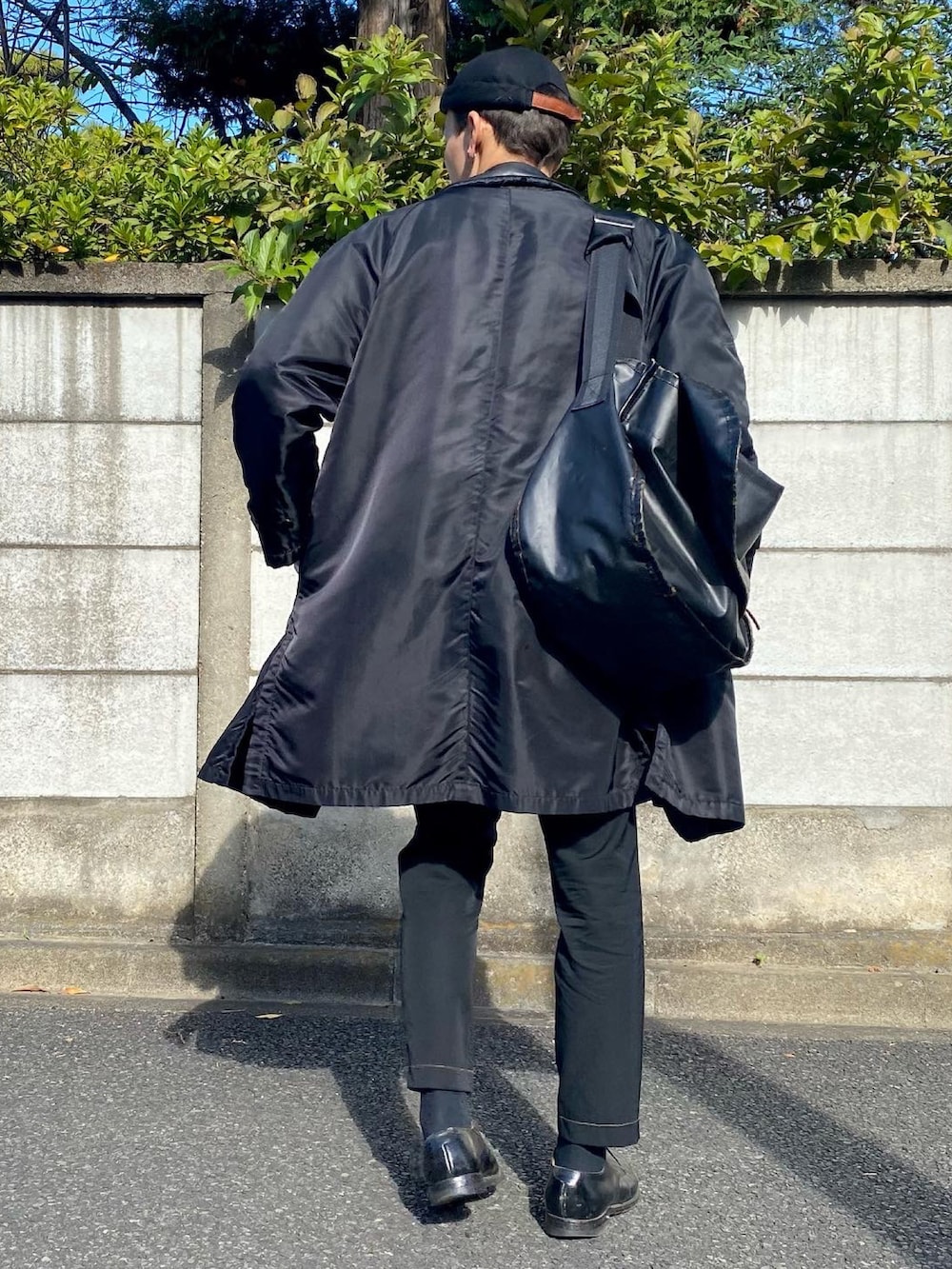 ブラック系のベスト、ホワイト系のTシャツ/カットソー、ブラック系のステンカラーコートを着用したメンズの秋コーディネートの2枚目の写真