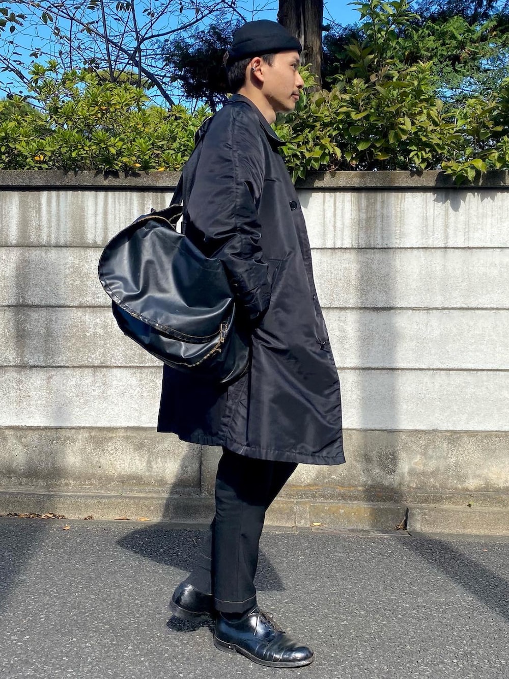 ブラック系のベスト、ホワイト系のTシャツ/カットソー、ブラック系のステンカラーコートを着用したメンズの秋コーディネートの3枚目の写真