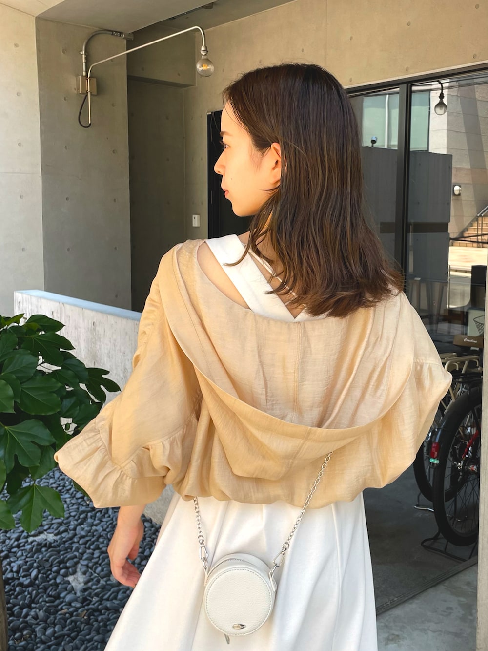 ベージュ系のブルゾン、ホワイト系のワンピースを着用したレディースの夏コーディネートの2枚目の写真