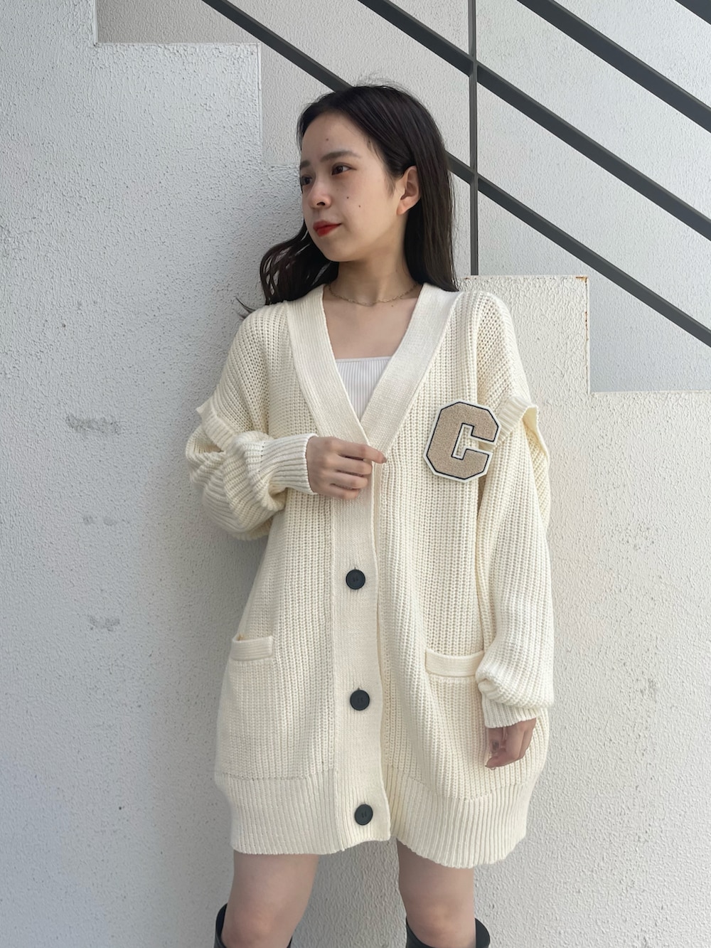 ホワイト系のカーディガン/ボレロ、ホワイト系のキャミソール、ブラック系のブーツを着用したレディースの夏コーディネートの3枚目の写真