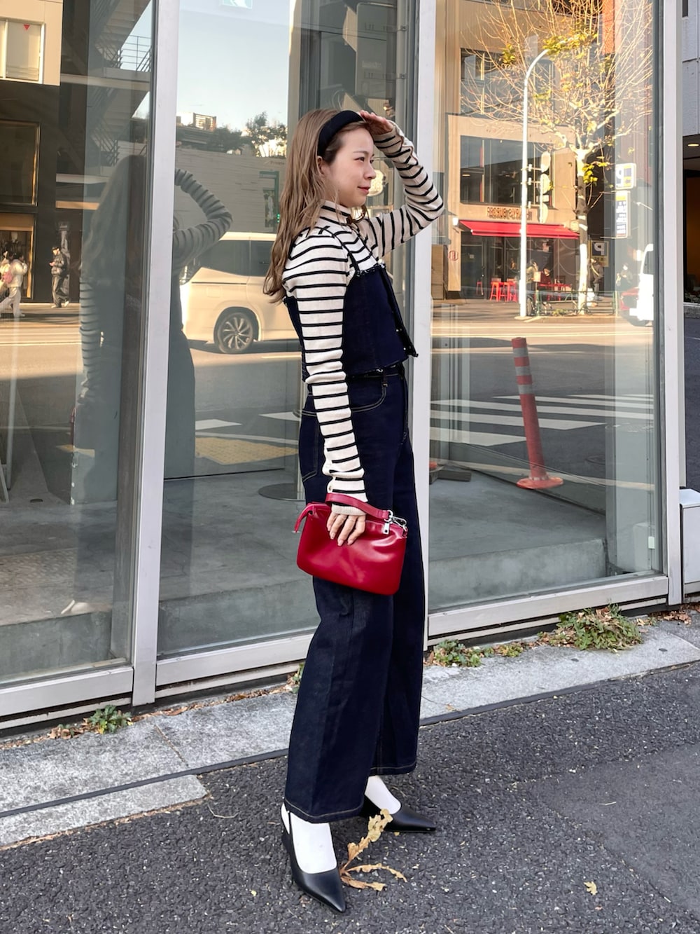 ブラック系のデニムパンツ、ホワイト系のニット/セーター、レッド系のショルダーバッグを着用したレディースの冬コーディネートの2枚目の写真