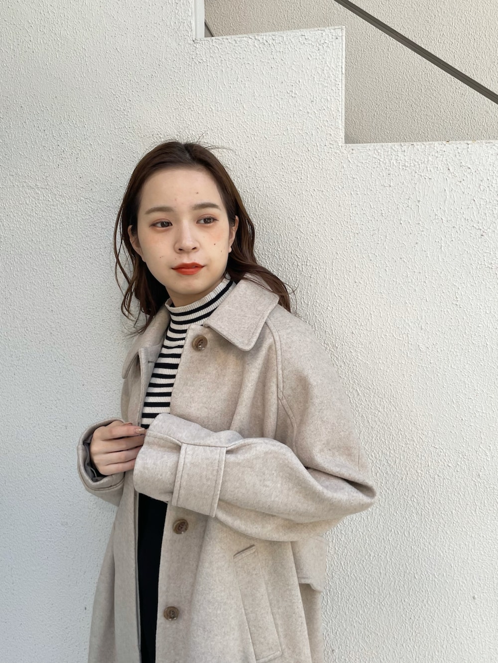 ベージュ系のステンカラーコート、ブラック系のブーツ、ブラック系のスカートを着用したレディースの秋コーディネートの3枚目の写真