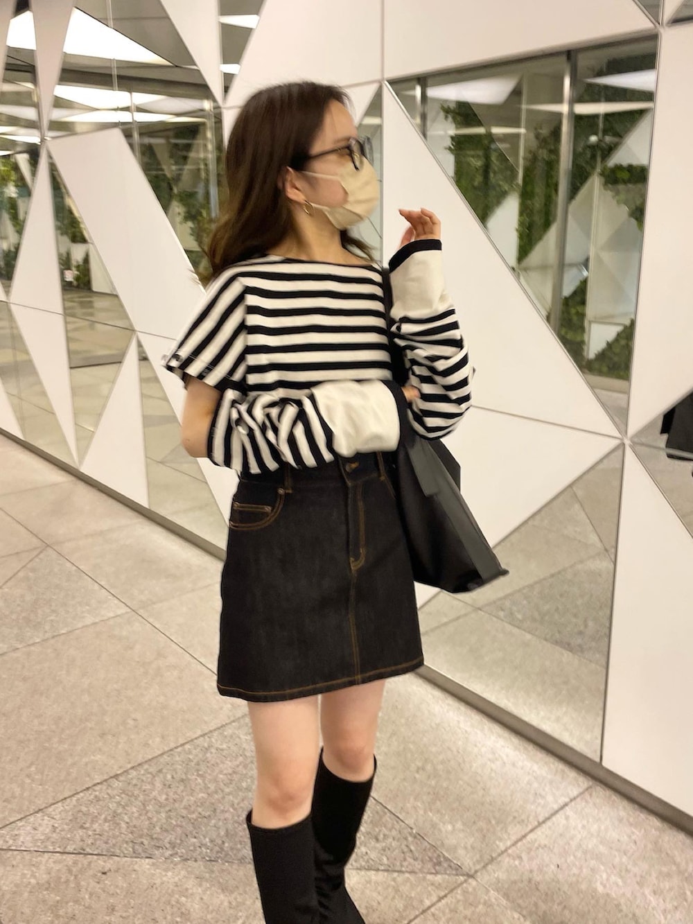 ホワイト系のTシャツ/カットソー、ブラック系のデニムスカートを着用したレディースの春コーディネートの2枚目の写真