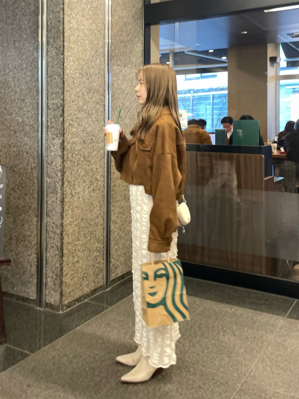 ベージュ系のスカート、イエロー系のブルゾン、ホワイト系のブーツを着用したレディースの春コーディネートの3枚目の写真