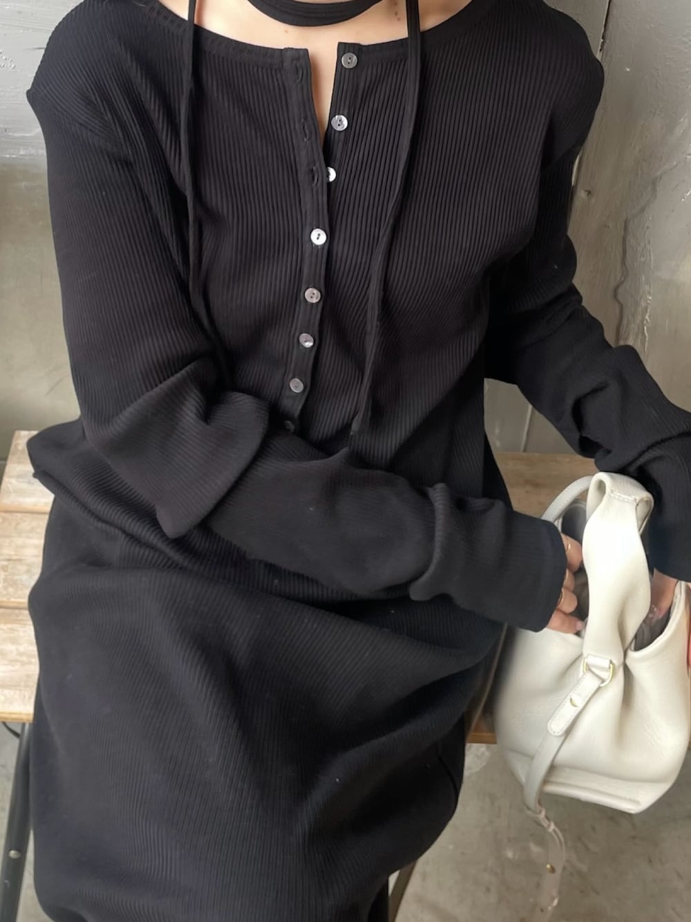 ブラック系のブーツ、ブラック系のワンピース、ホワイト系のハンドバッグを着用したレディースの春コーディネートの3枚目の写真