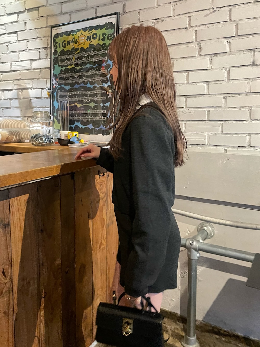 グレー系のカーディガン/ボレロ、ブラック系のショルダーバッグ、ホワイト系のベストを着用したレディースの春コーディネートの2枚目の写真