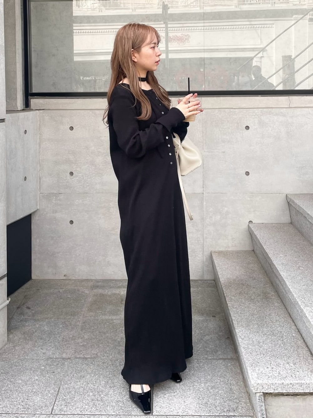 ブラック系のブーツ、ブラック系のワンピース、ホワイト系のハンドバッグを着用したレディースの春コーディネートの4枚目の写真