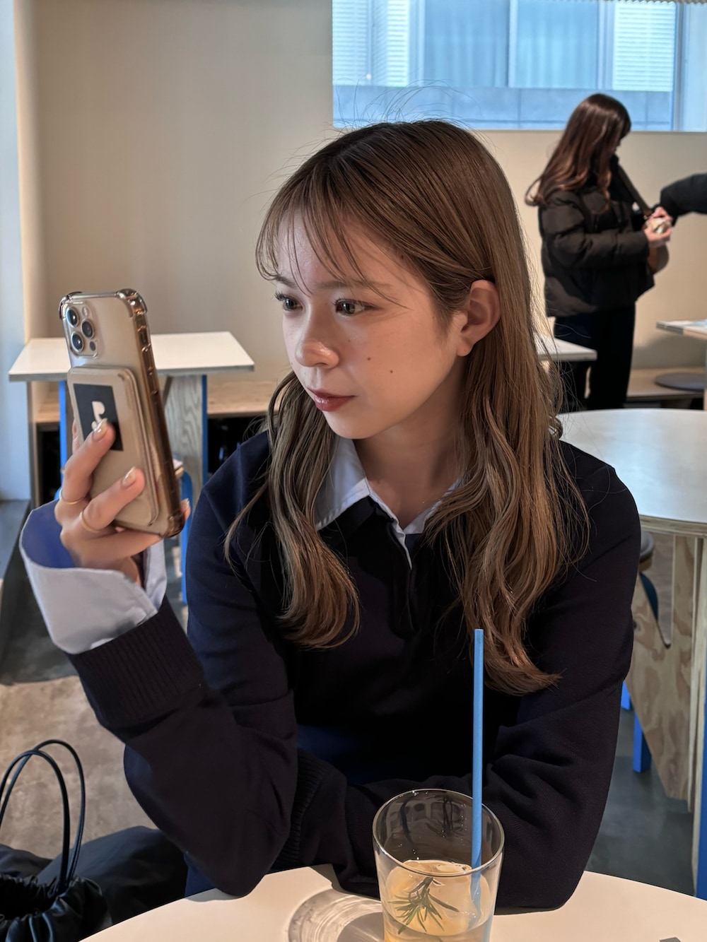 ブルー系のニット/セーター、ブルー系のデニムスカート、ホワイト系のスニーカーを着用したレディースの冬コーディネートの5枚目の写真