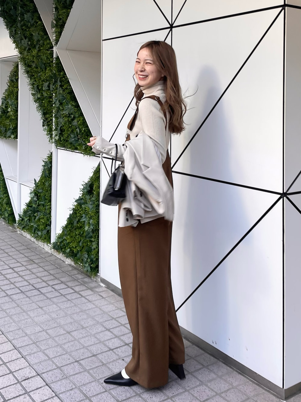 ブラウン系のサロペット/オーバーオール、ブラック系のショルダーバッグ、ホワイト系のニット/セーターを着用したレディースの冬コーディネートの3枚目の写真